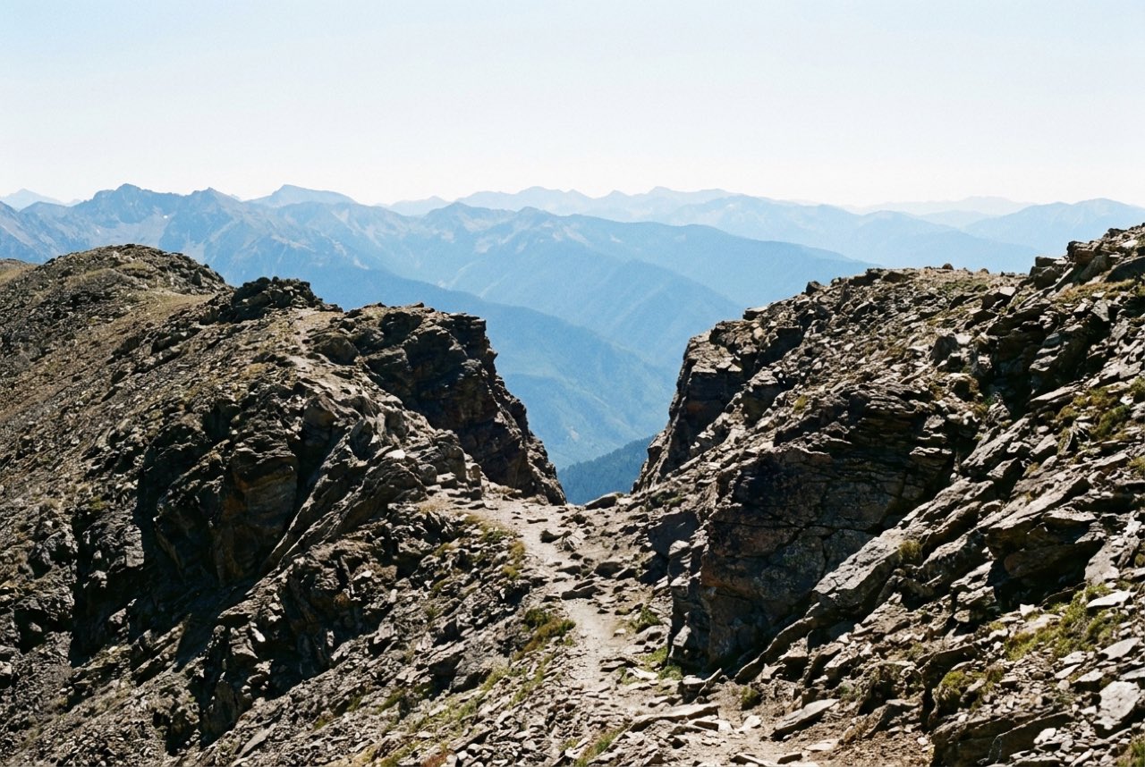 Midday: a high notch in a bare ridge with successive blue ranges visible through it, thin clear mountain air